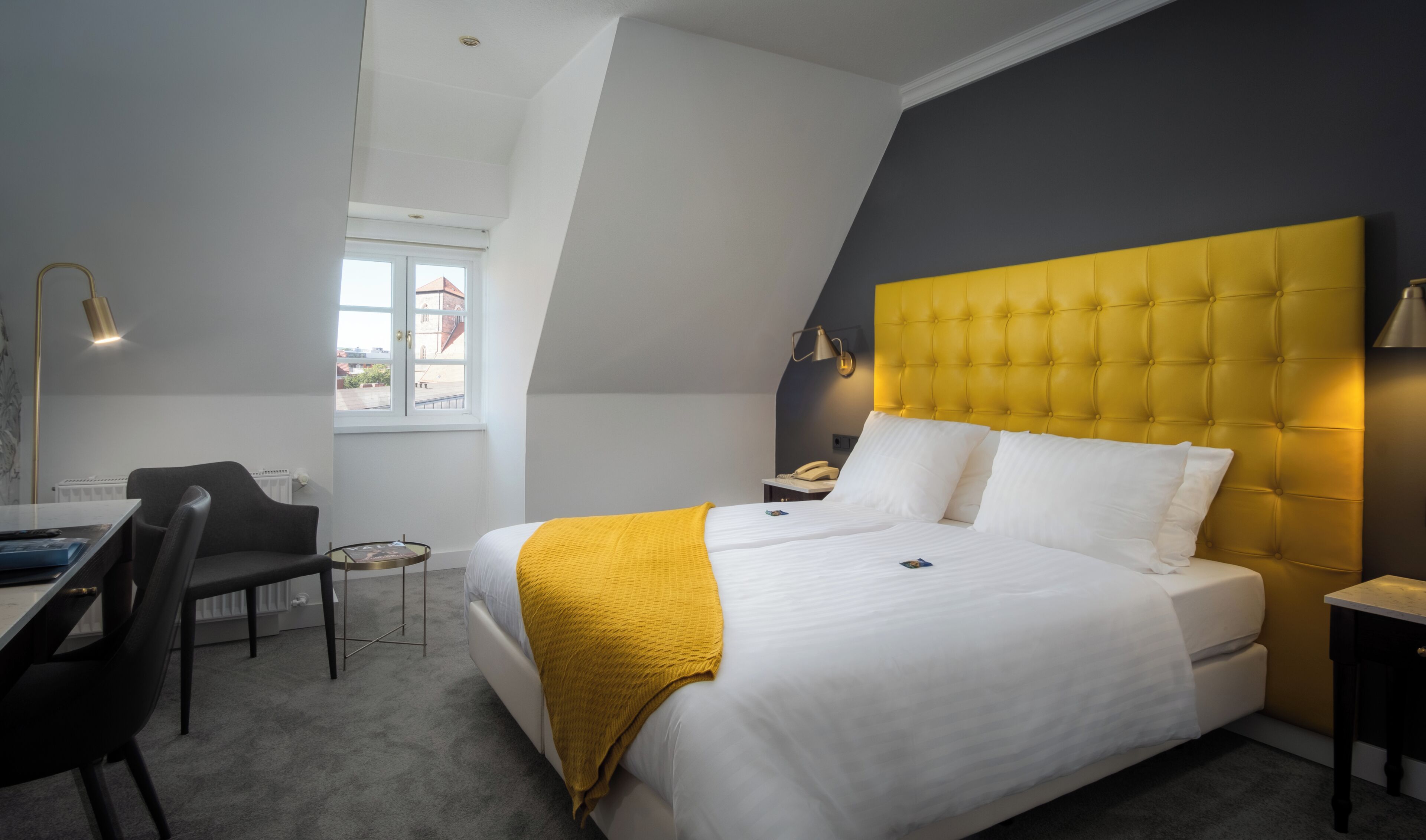 Een moderne hotelkamer met een bed, bureau, stoel en een raam met uitzicht.