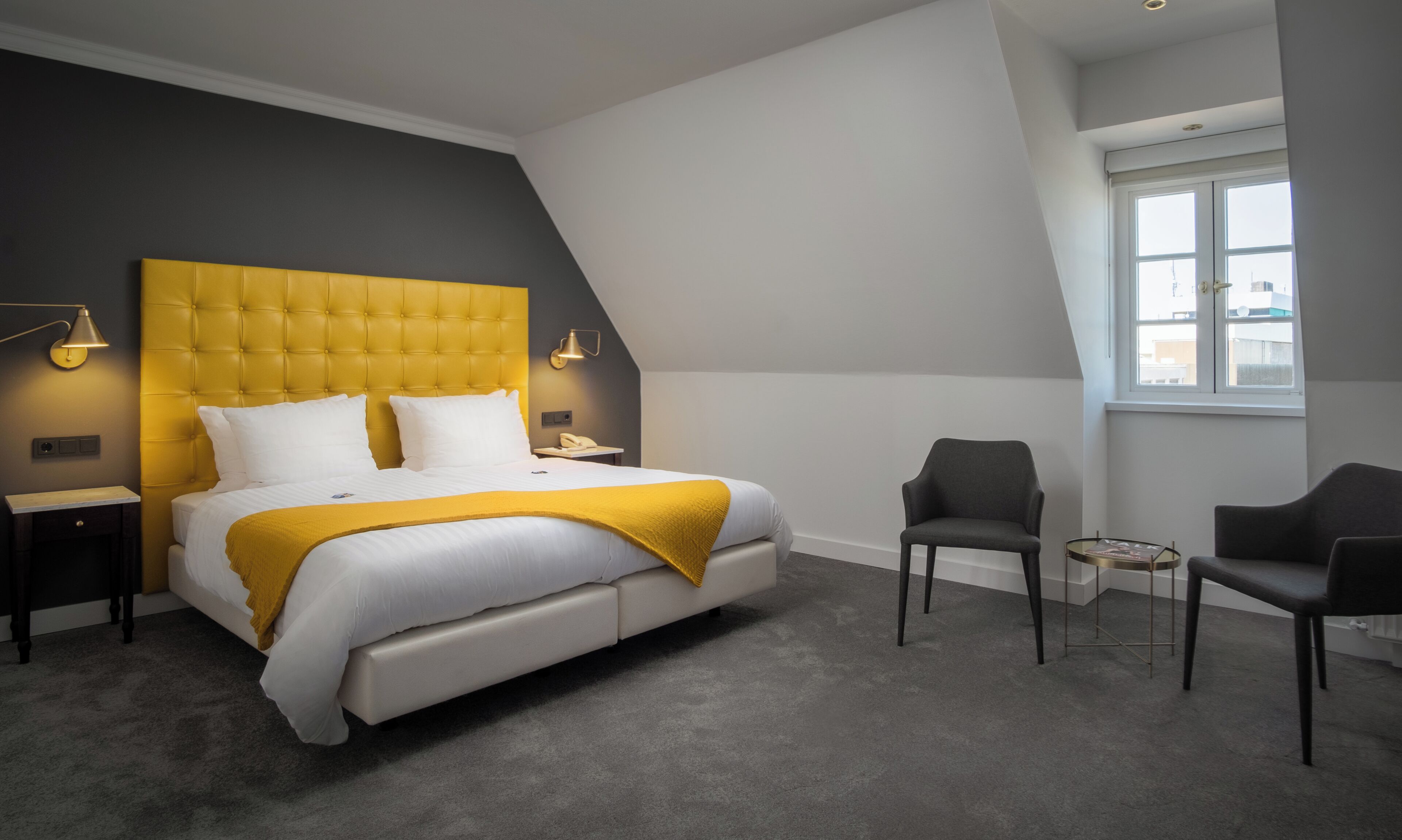 Ein Schlafzimmer mit einem Bett, zwei Nachttischen, einem Sessel und einem Fenster.