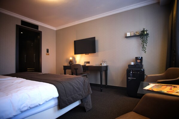 A hotel room with a bed, desk, chair, TV, and a coffee machine. - Van der Valk Hotel Hildesheim (Hildesheim)
