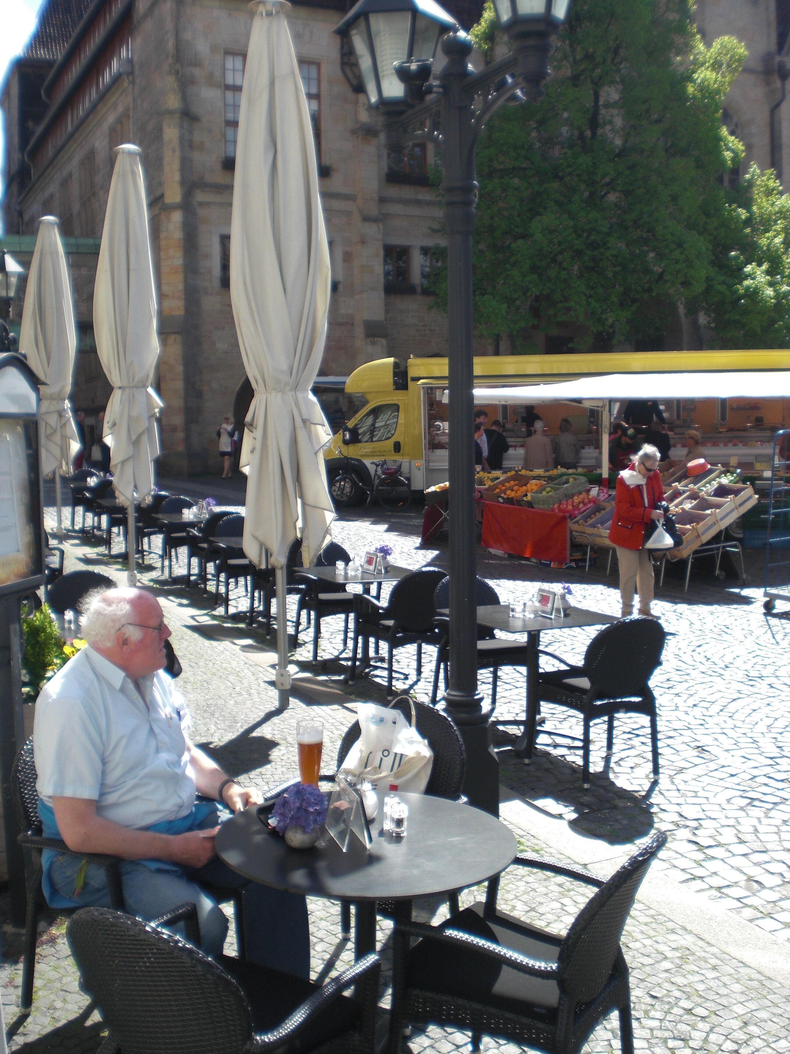 Ein Straßencafé mit Tischen und Stühlen, ein Imbisswagen und eine gepflasterte Straße.