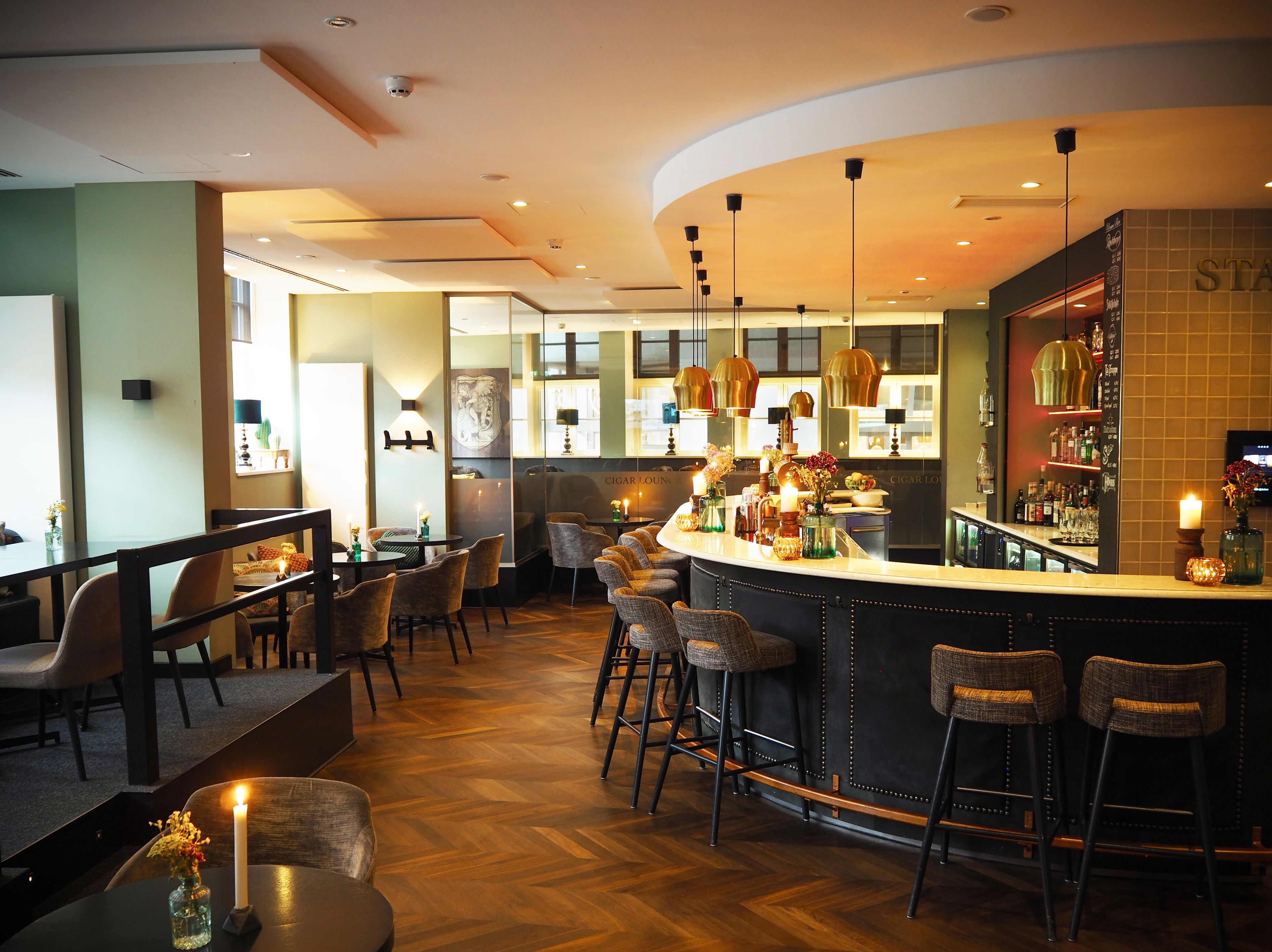A bar area with high stools, a curved counter, and a seating area with tables and chairs.