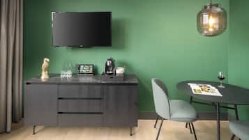 Ein modernes Zimmer mit einem dunklen Holztisch, einem Flachbildfernseher, einer Pendelleuchte und einem runden Tisch mit Stühlen.