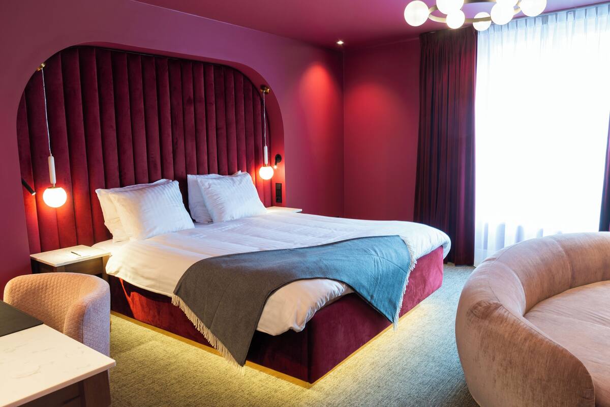 Une chambre d’hôtel moderne, dotée d’un grand lit, d’un bureau et d’un fauteuil confortable.