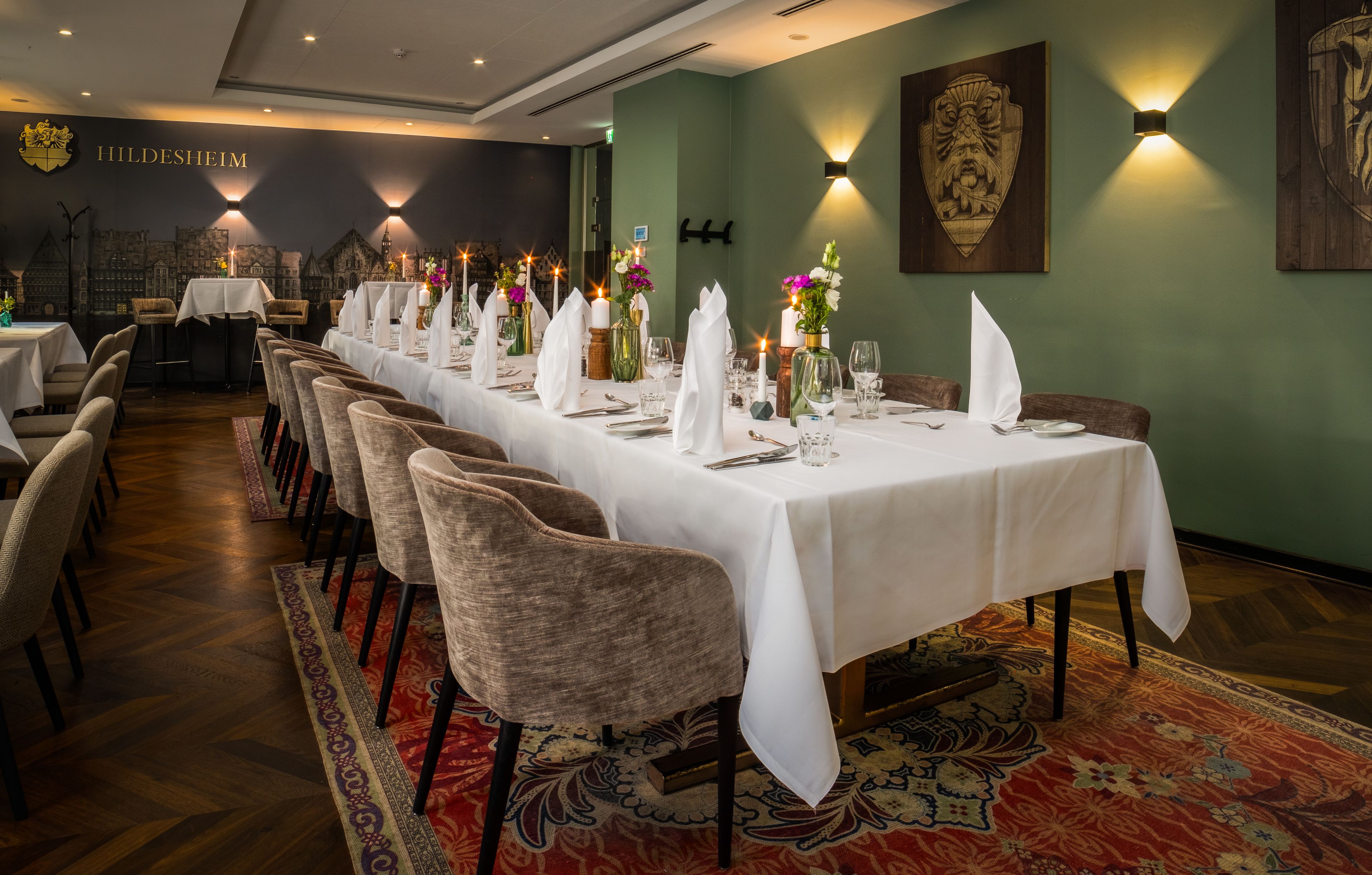 A long dining table with white tablecloths and chairs, set with plates, glasses, and flowers.