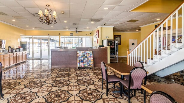 A restaurant with a patterned tile floor, a central island with a display of magazines, and a staircase with white railings. - Rodeway Inn Arlington Entertainment District Area (Arlington)