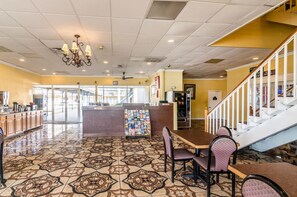 A restaurant with a patterned tile floor, a central island with a display of magazines, and a staircase with white railings. - Rodeway Inn Arlington Entertainment District Area (Arlington)