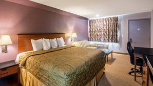 A hotel room with a large bed, a desk, a chair, and a small table. - Rodeway Inn Arlington Entertainment District Area (Arlington)