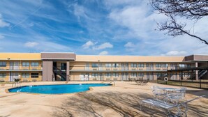 A hotel with a swimming pool, outdoor seating, and a building with multiple windows. - Rodeway Inn Arlington Entertainment District Area (Arlington)