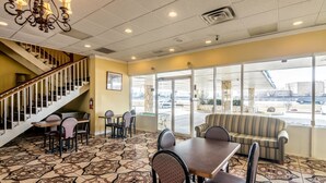 A restaurant with a staircase, dining tables, chairs, and a large window with a view of the parking lot. - Rodeway Inn Arlington Entertainment District Area (Arlington)