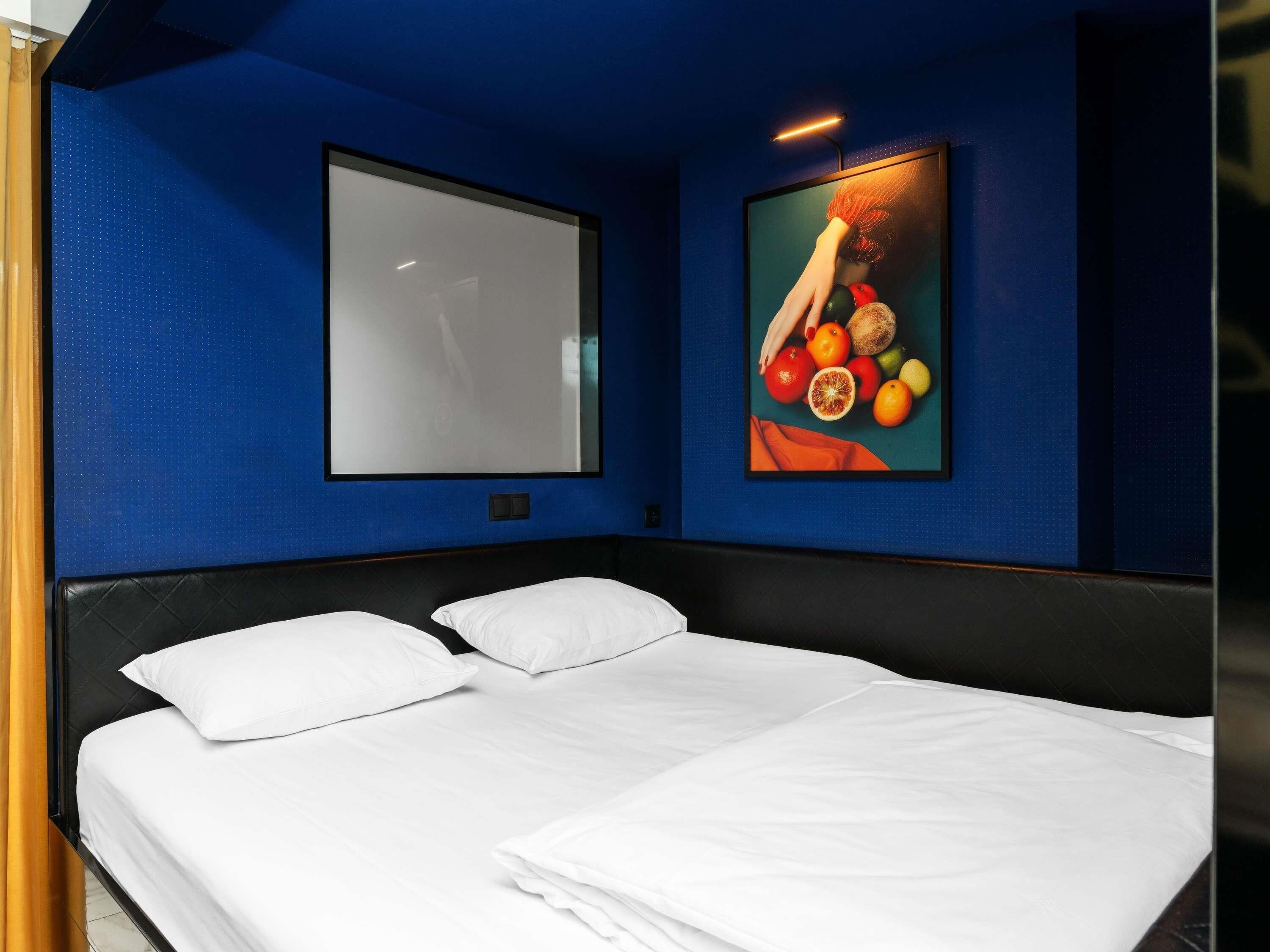 A hotel room with a bed, a large window, and a wall-mounted artwork.