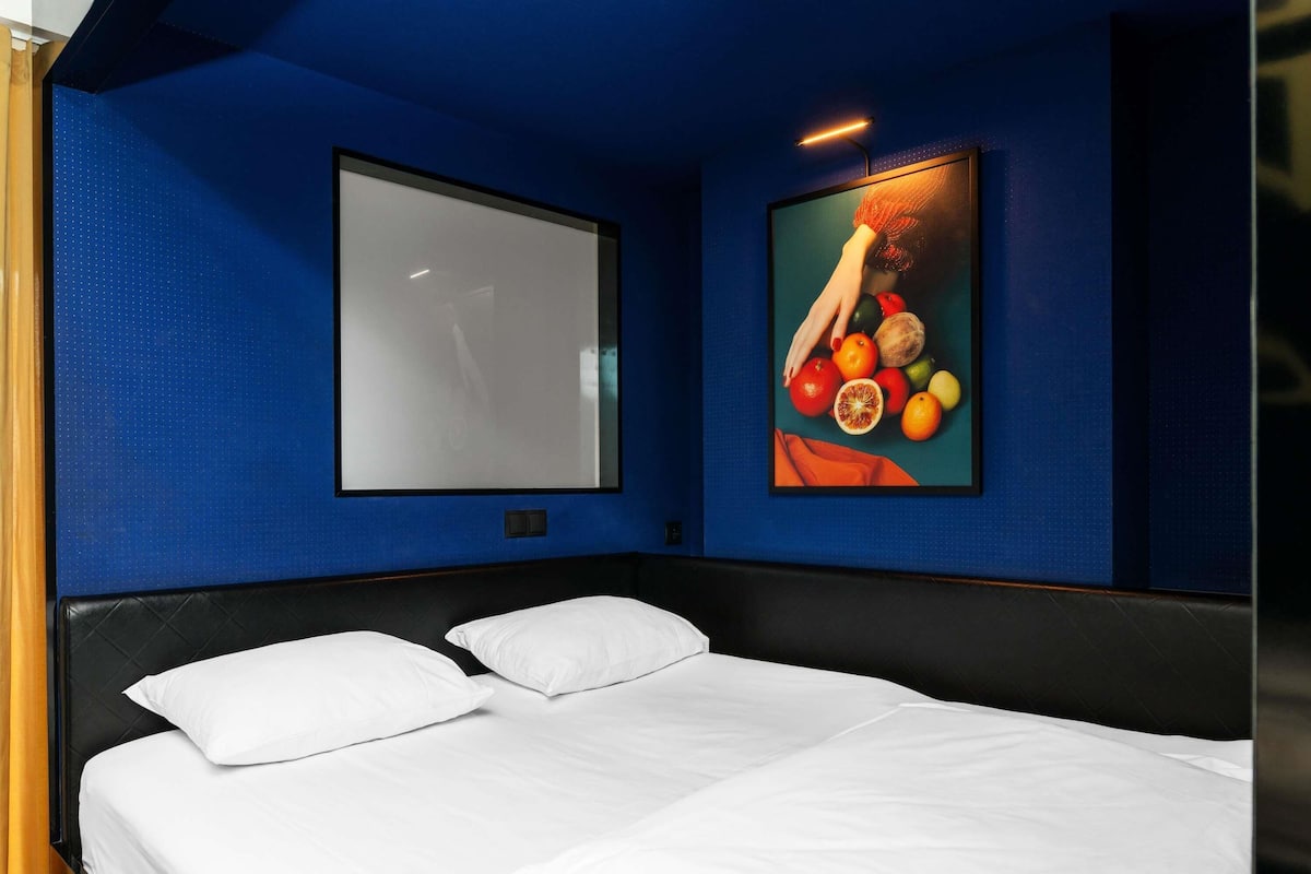 Une chambre d’hôtel avec un lit, une grande fenêtre et une œuvre d’art accrochée au mur.