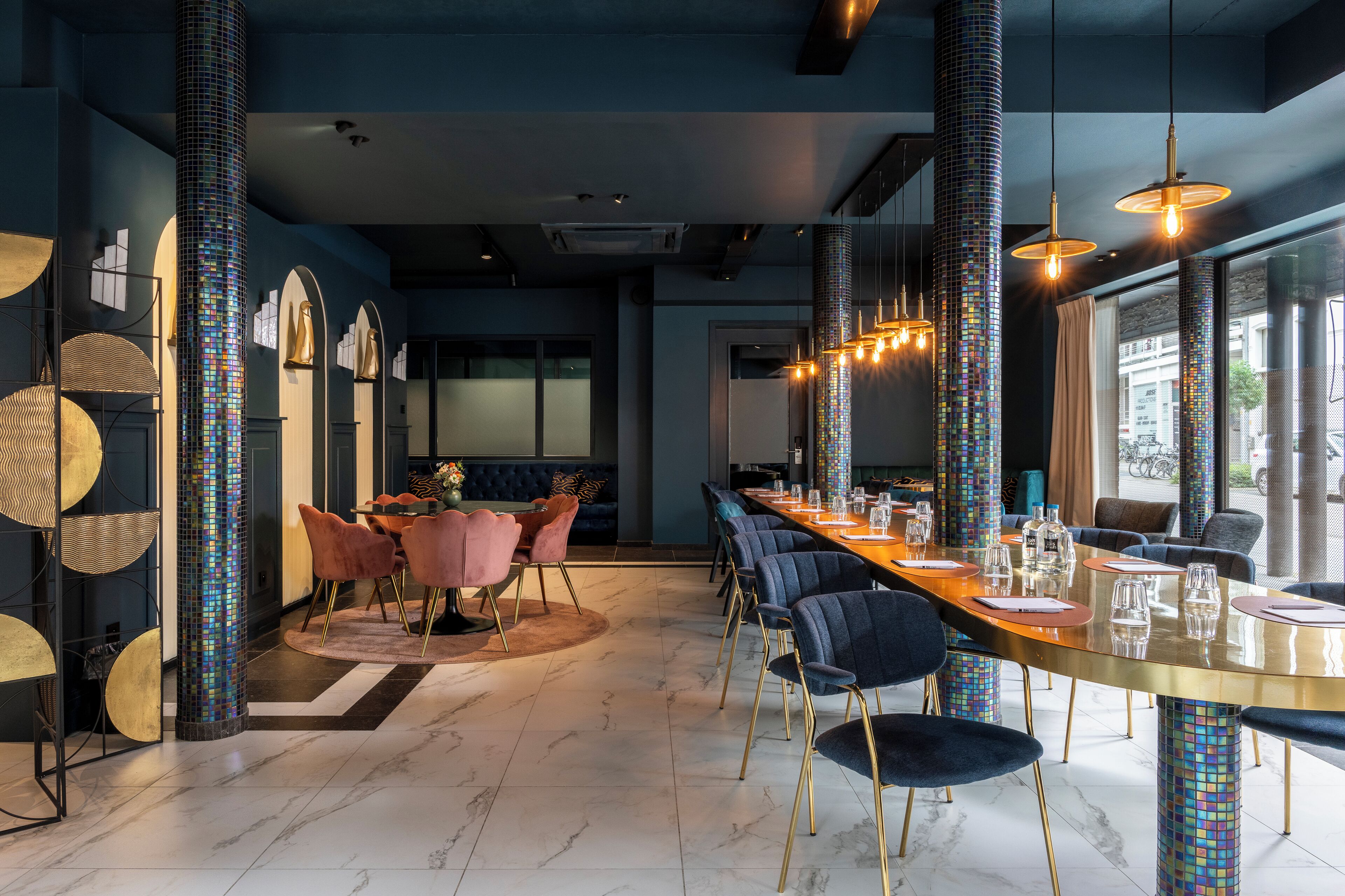 A modern dining area with a long table, chairs, and pendant lighting.