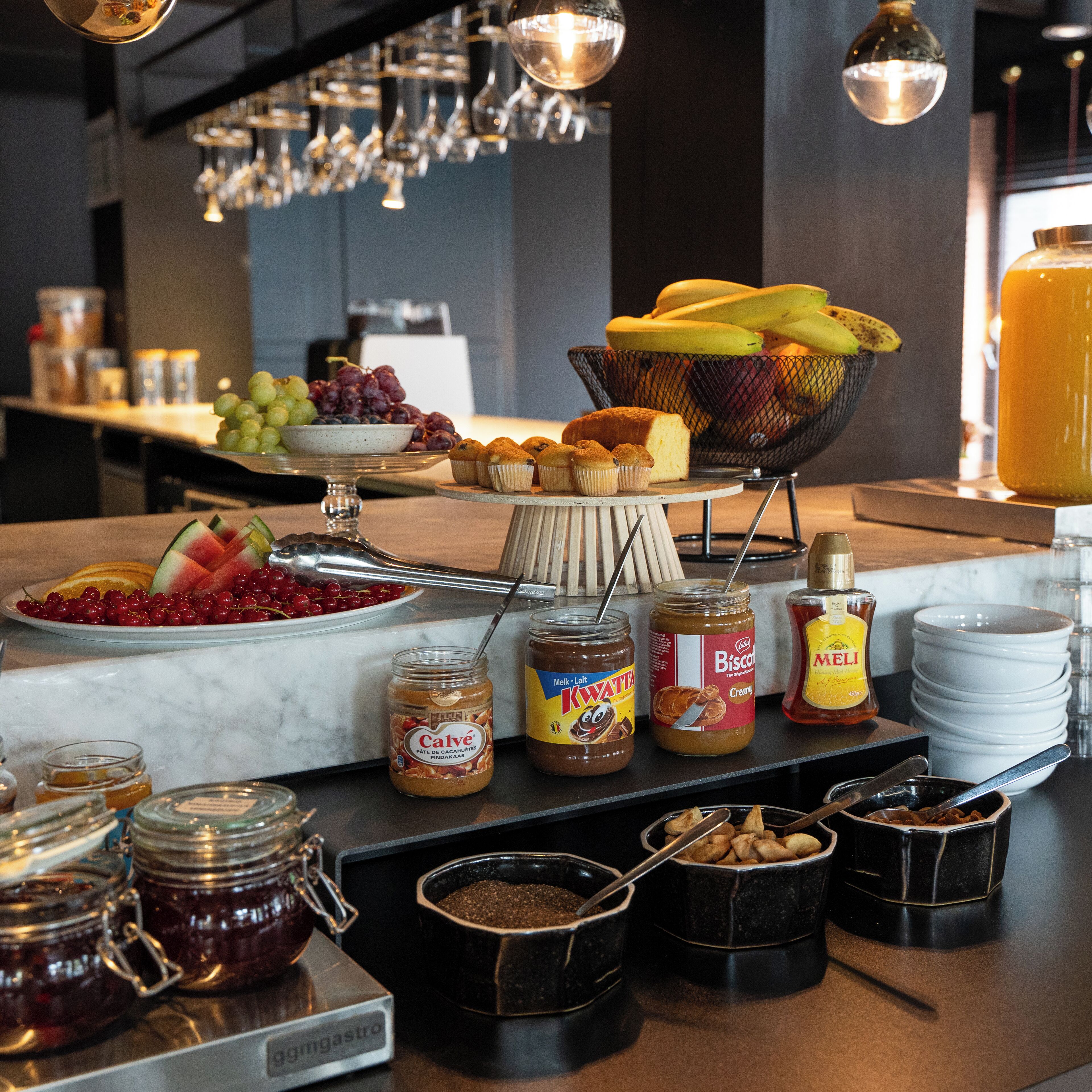 Un bufé de desayuno con diversas opciones de comida, entre ellas frutas, bollería y salsas.