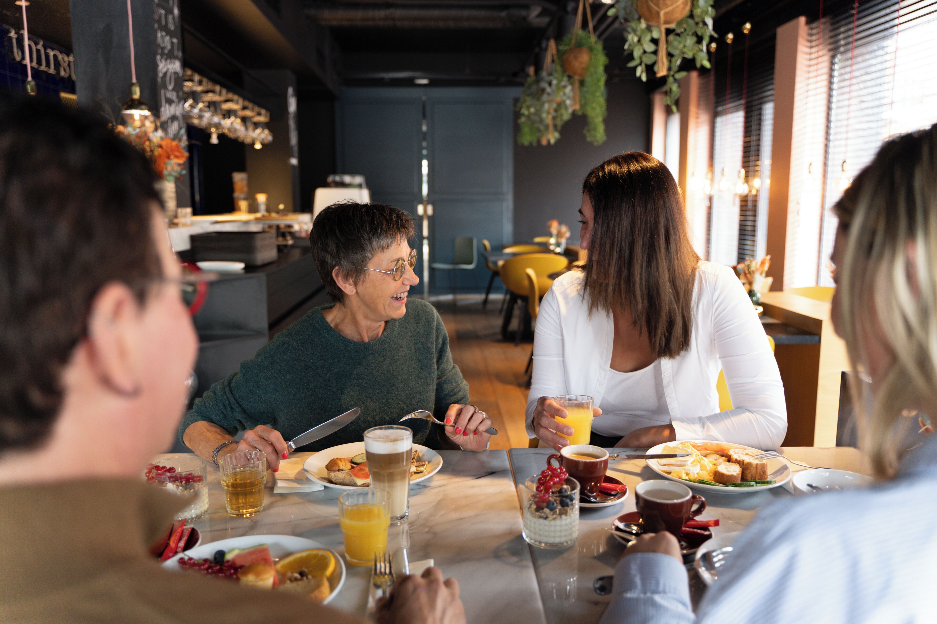 Un grupo de personas comiendo en una mesa con diversos alimentos y bebidas para el desayuno.