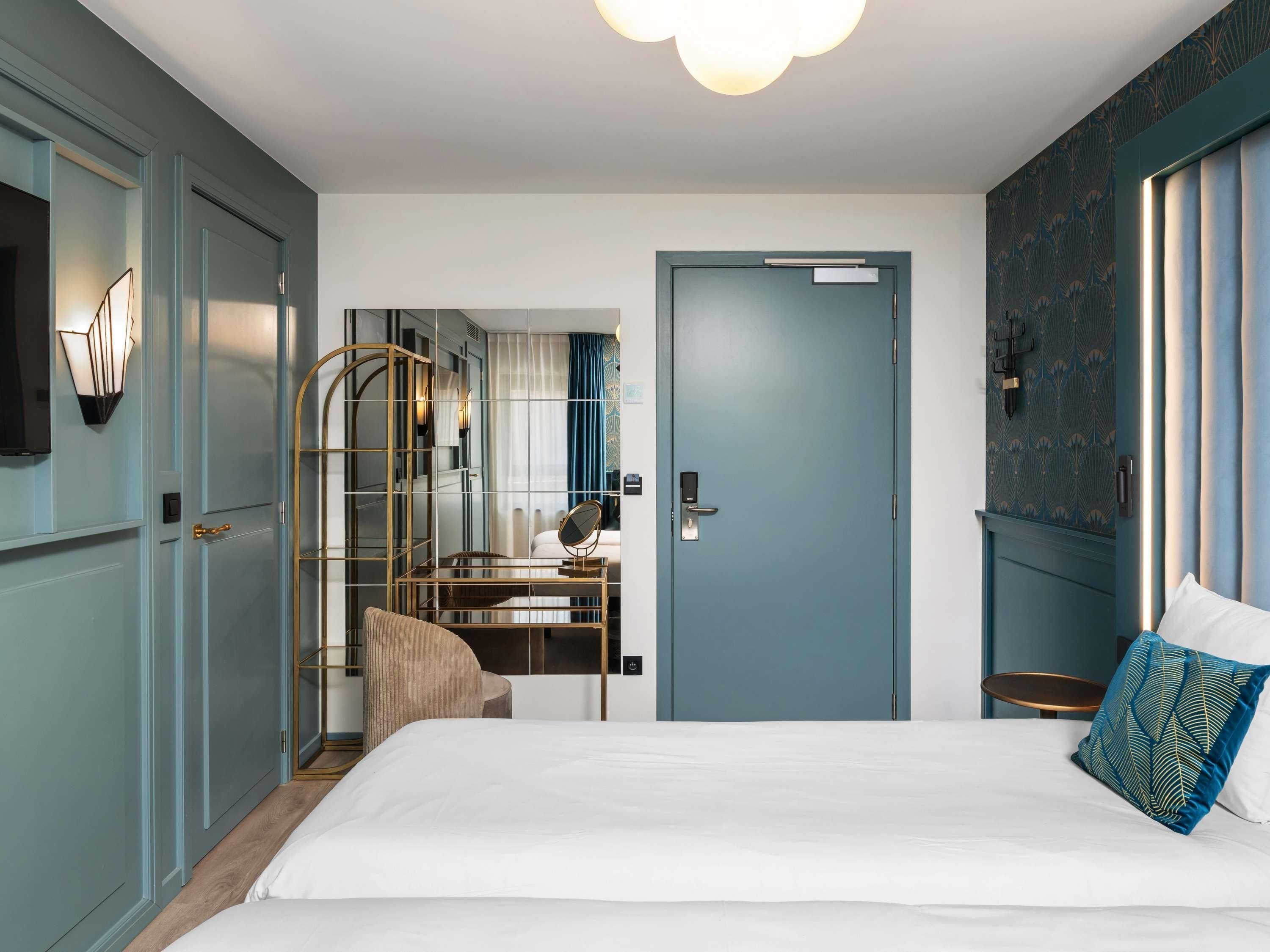 Een slaapkamer met een bed, een bureau, een stoel, een spiegel en een deur.