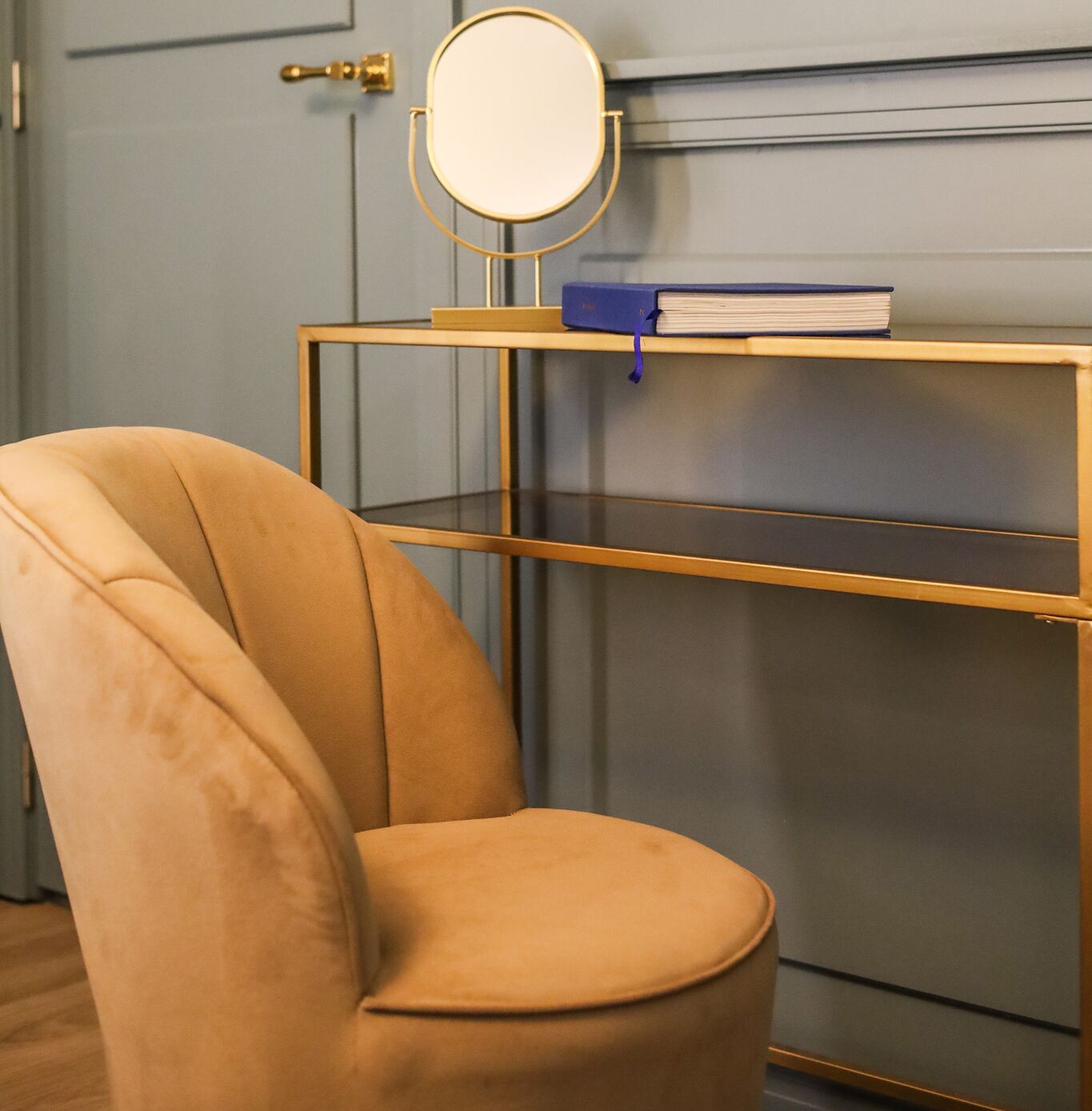 Une chaise au dossier arrondi et un miroir à cadre doré posé sur une étagère.