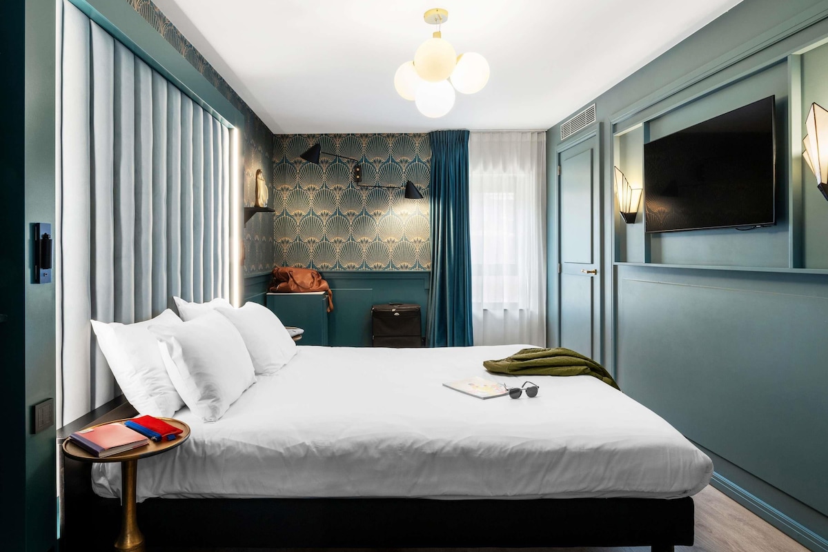 Une chambre d’hôtel moderne avec un grand lit, une table de chevet et un téléviseur fixé au mur.