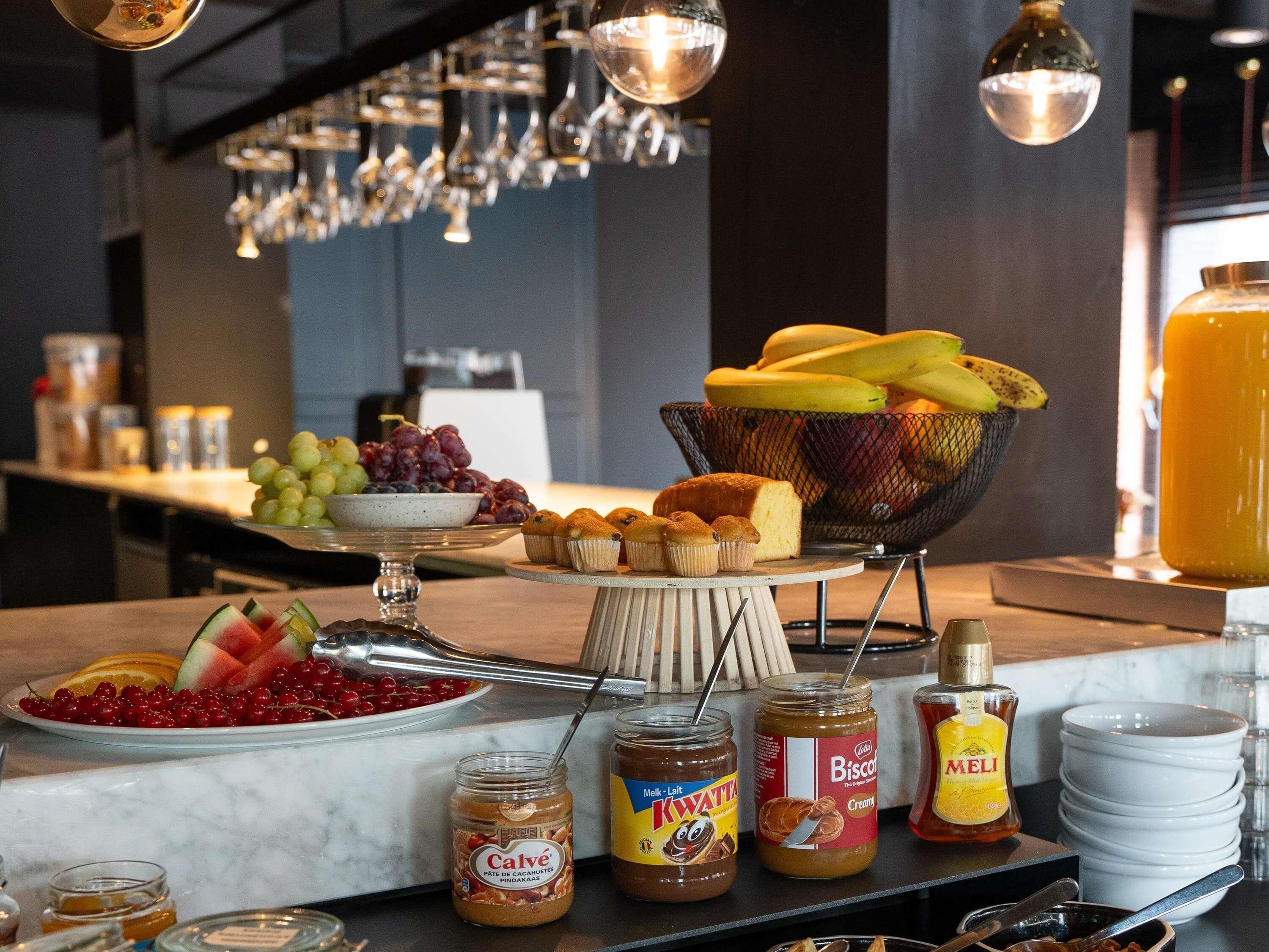 Un bufé de desayuno con diversas frutas, bollería y salsas.