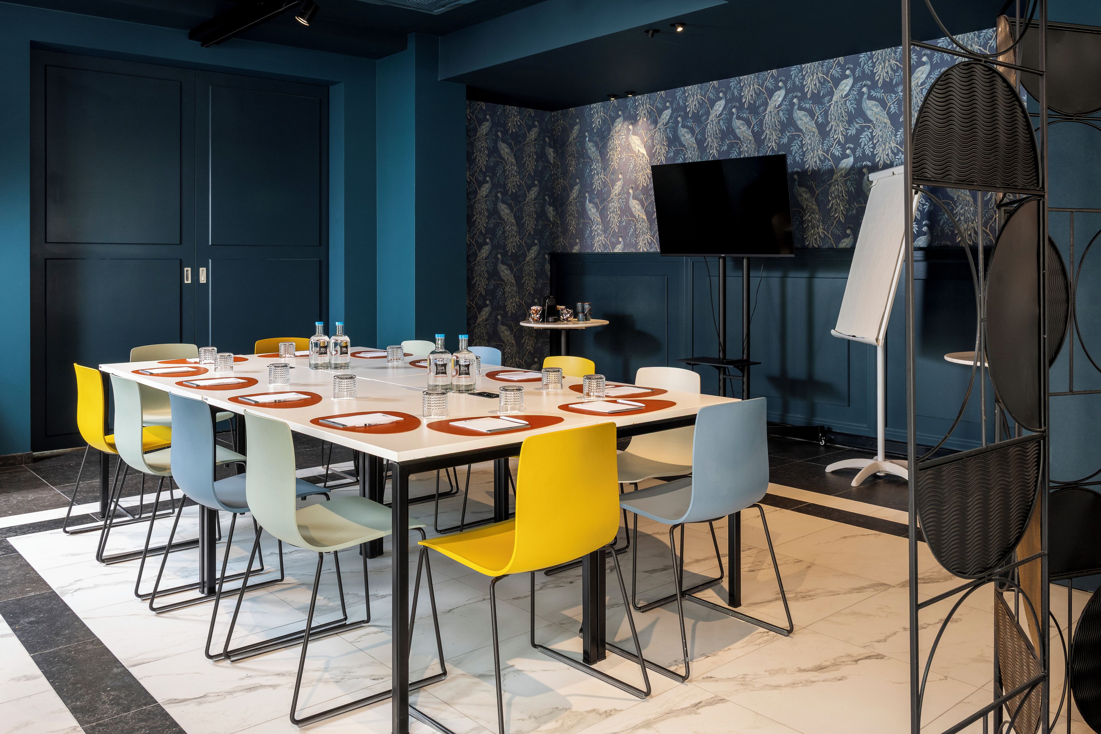 A conference room with a long table, multiple chairs, a television, and a projector.