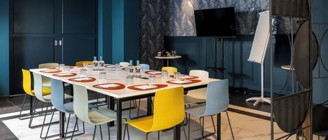 A conference room with a long table, multiple chairs, a television, and a projector.