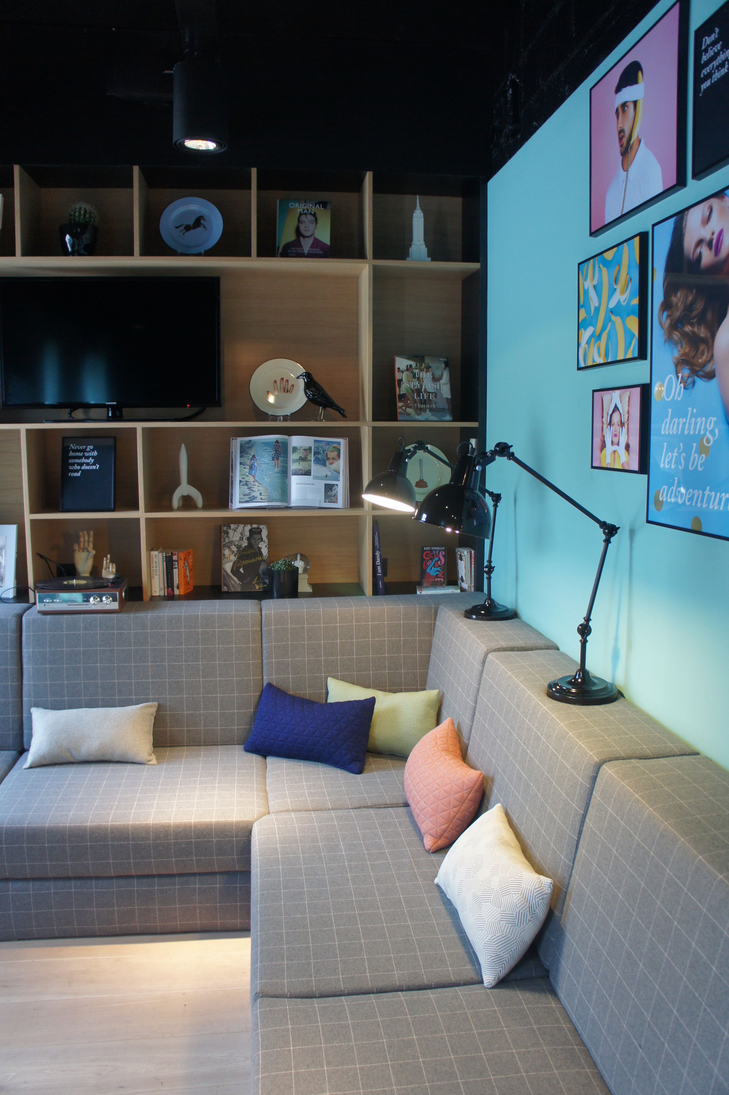 Una sala de estar moderna con un sofá seccional, un televisor de pantalla plana y una estantería llena de libros y objetos decorativos.