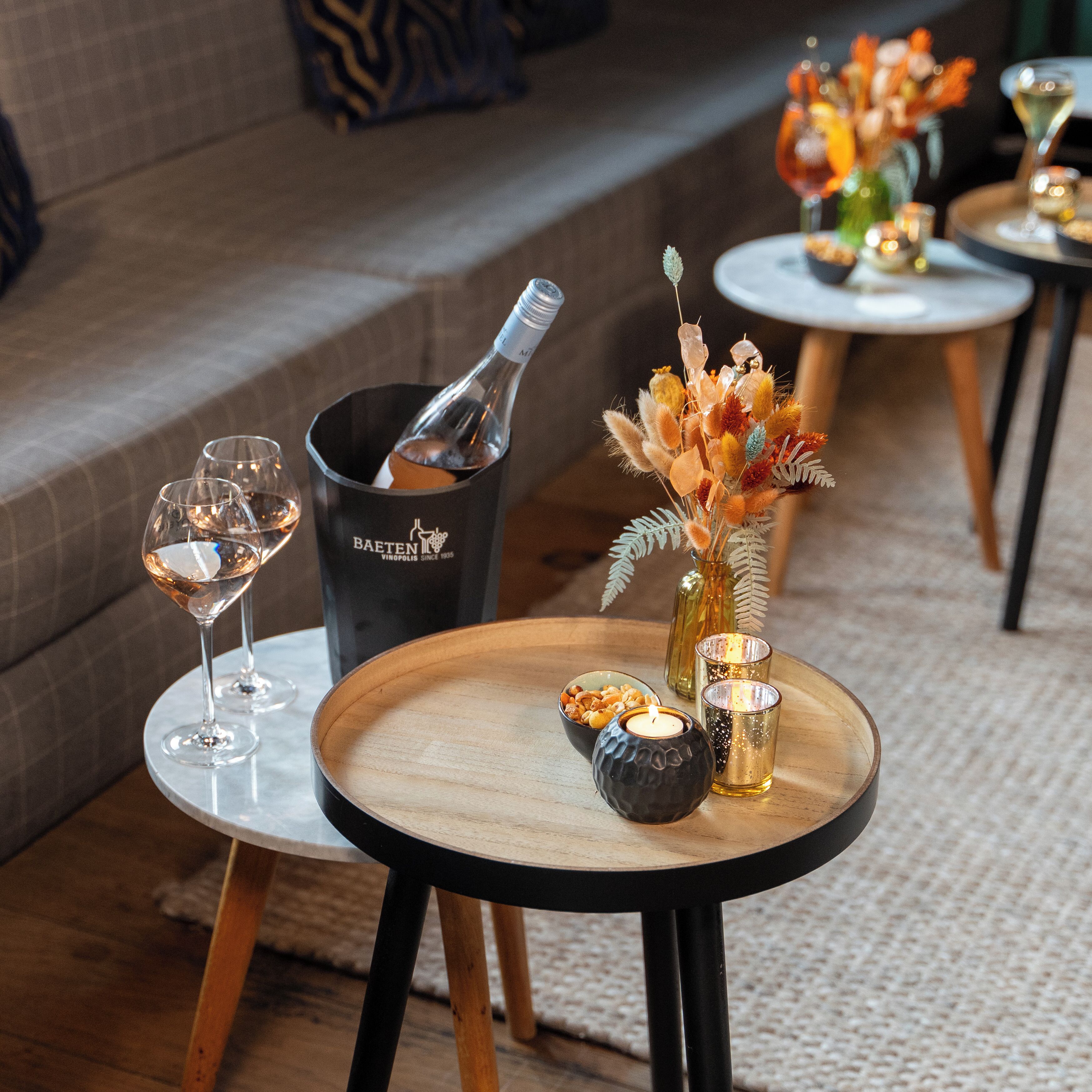 A table with a bottle of champagne, a candle, and a decorative vase.