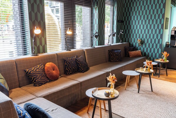 Relax in the lounge area with plush seating and a small table, surrounded by a geometric patterned wall and large windows.