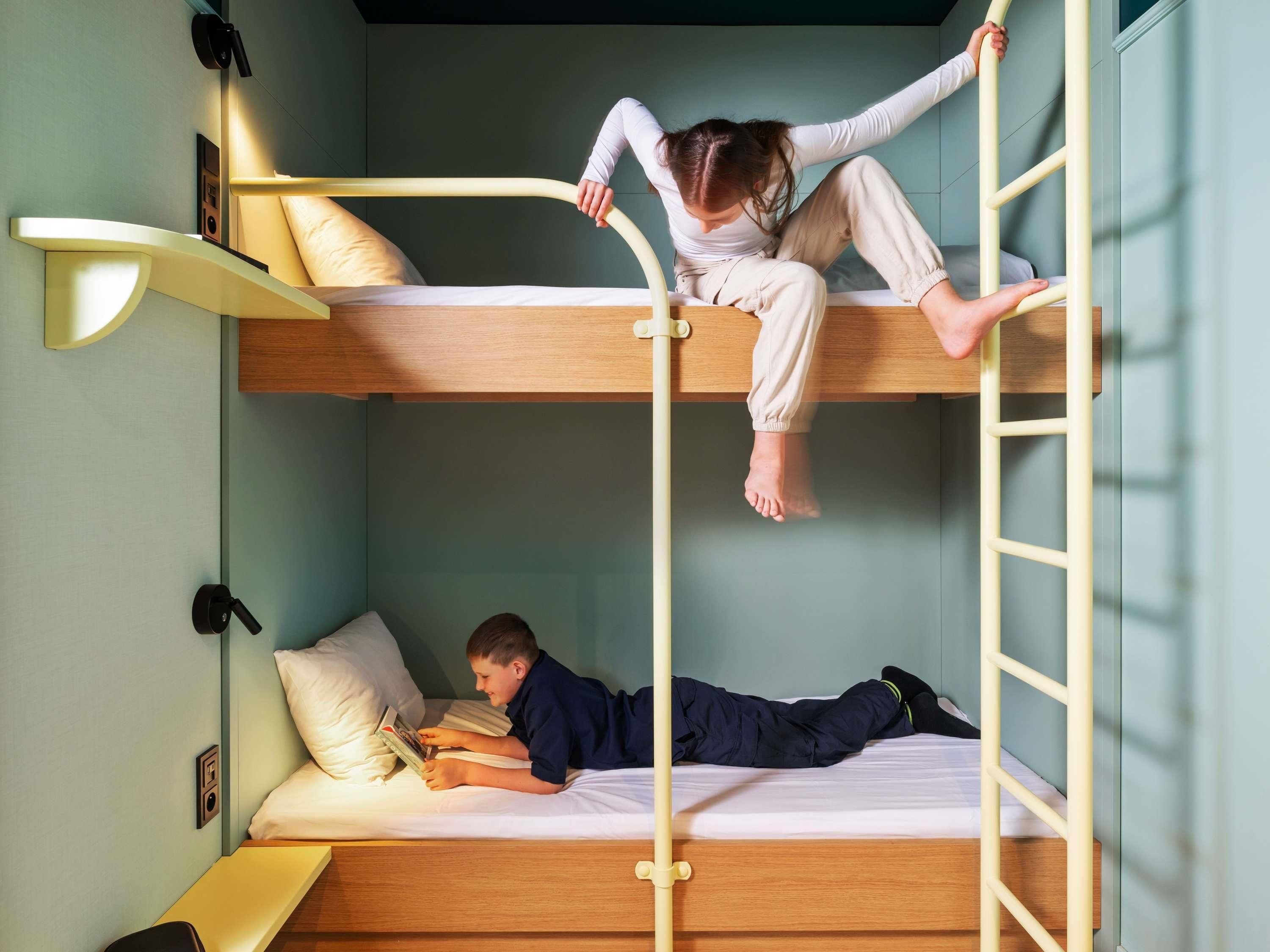 Een slaapkamer met een stapelbed, een nachtkastje en een lamp.