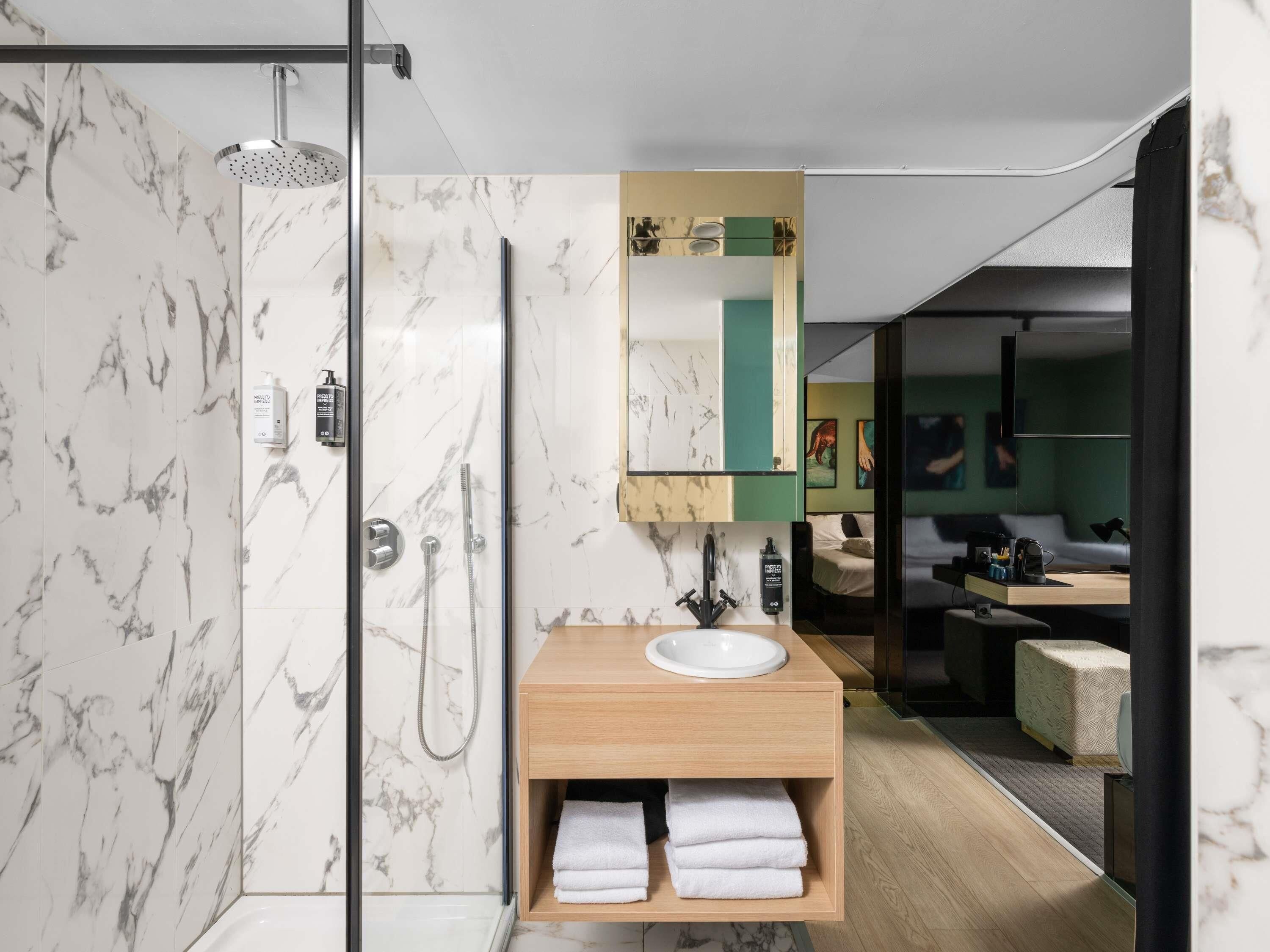 Een moderne badkamer met een douche met glazen wand, een houten wastafelmeubel en een spiegel erboven.