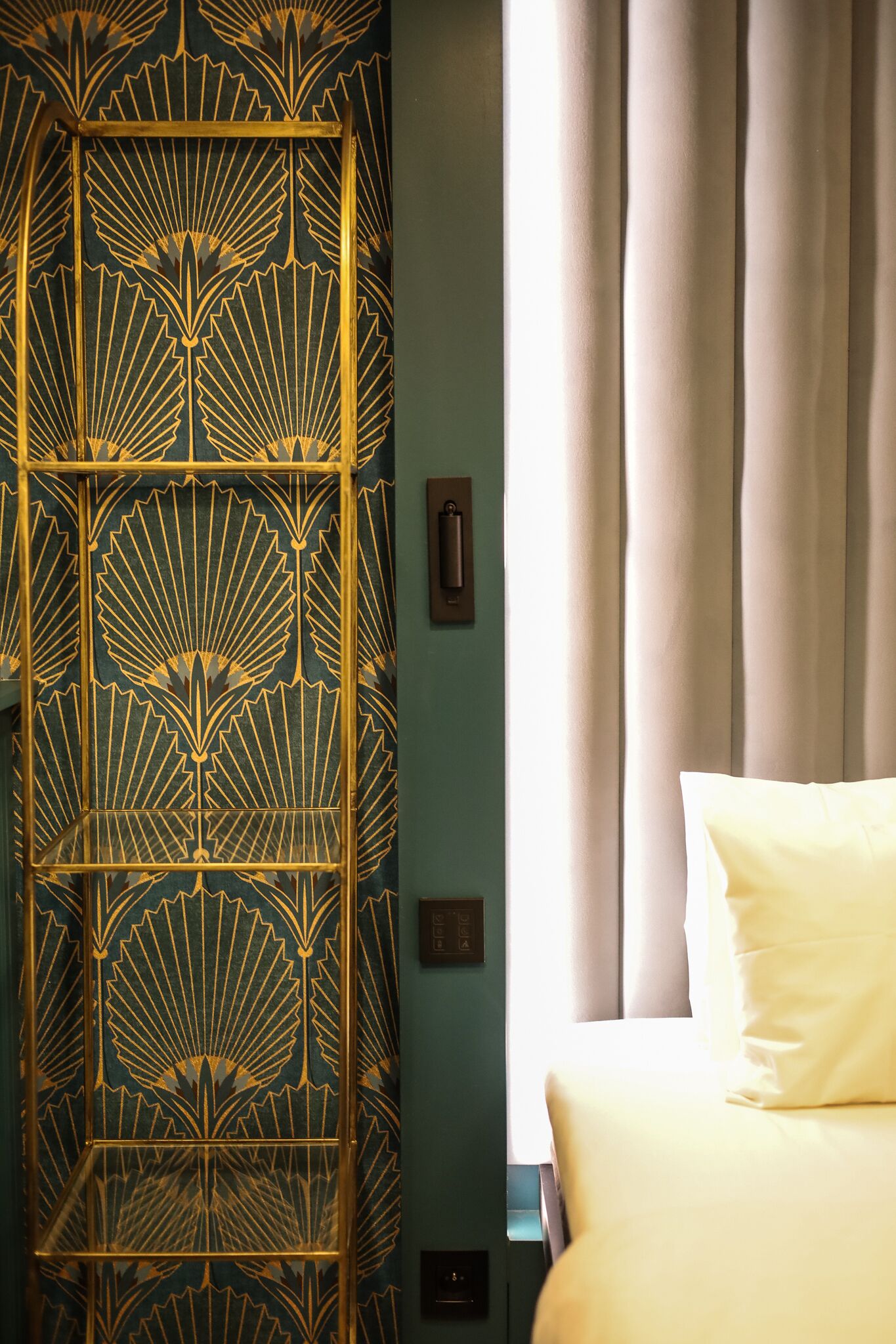 Una stanza con un letto, un paravento decorativo e una finestra con tende.