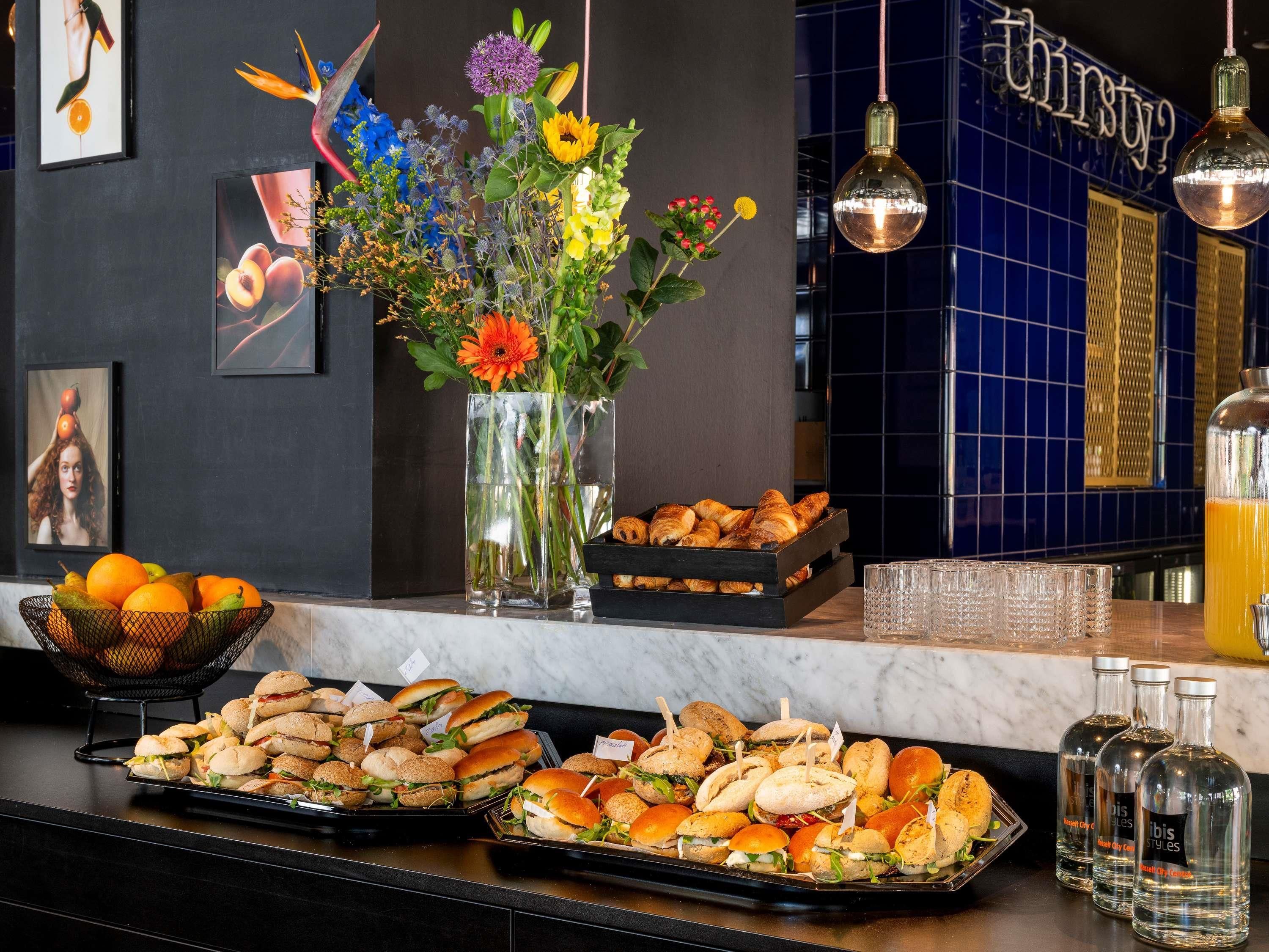 Un espace bar proposant une variété de plats, une composition florale et un panneau indiquant : « Vous avez soif ? ».