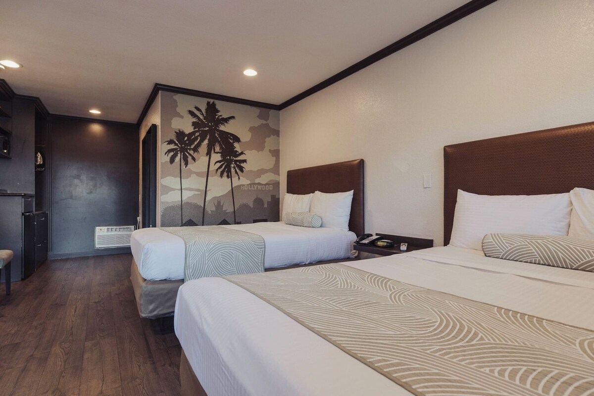 A hotel room with two beds, a desk, and a wall mural.