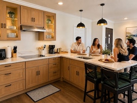 Una cucina moderna con mobili in legno, un'isola grande e illuminazione a sospensione.