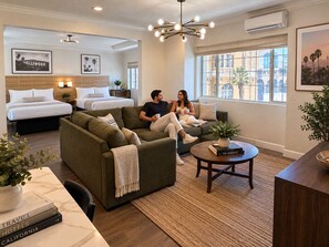 A hotel room with a bed, a sofa, a coffee table, and a large window with a view. - The Dixie Hollywood (Los Angeles)