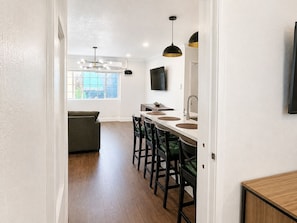 A modern kitchen with a central island, bar stools, a flat-screen TV, and pendant lighting. - The Dixie Hollywood (Los Angeles)