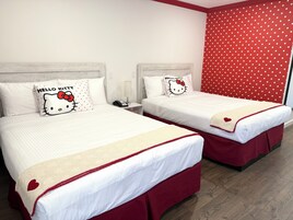 Twee bedden met Hello Kitty kussens, een rood stippen gordijn en een houten vloer.