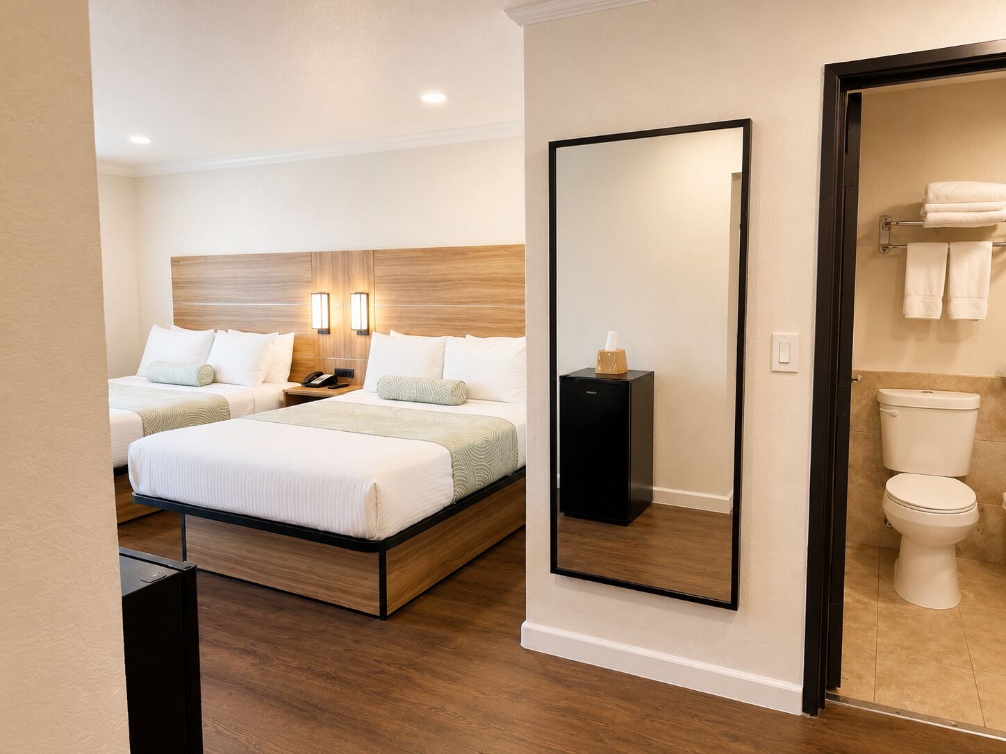 Quarto de hotel com uma cama, mesa de cabeceira, abajur e um espelho.