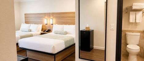 Quarto de hotel com uma cama, mesa de cabeceira, abajur e um espelho.