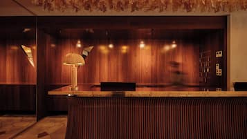 A reception desk with a lamp, wooden panel walls, and a patterned floor.