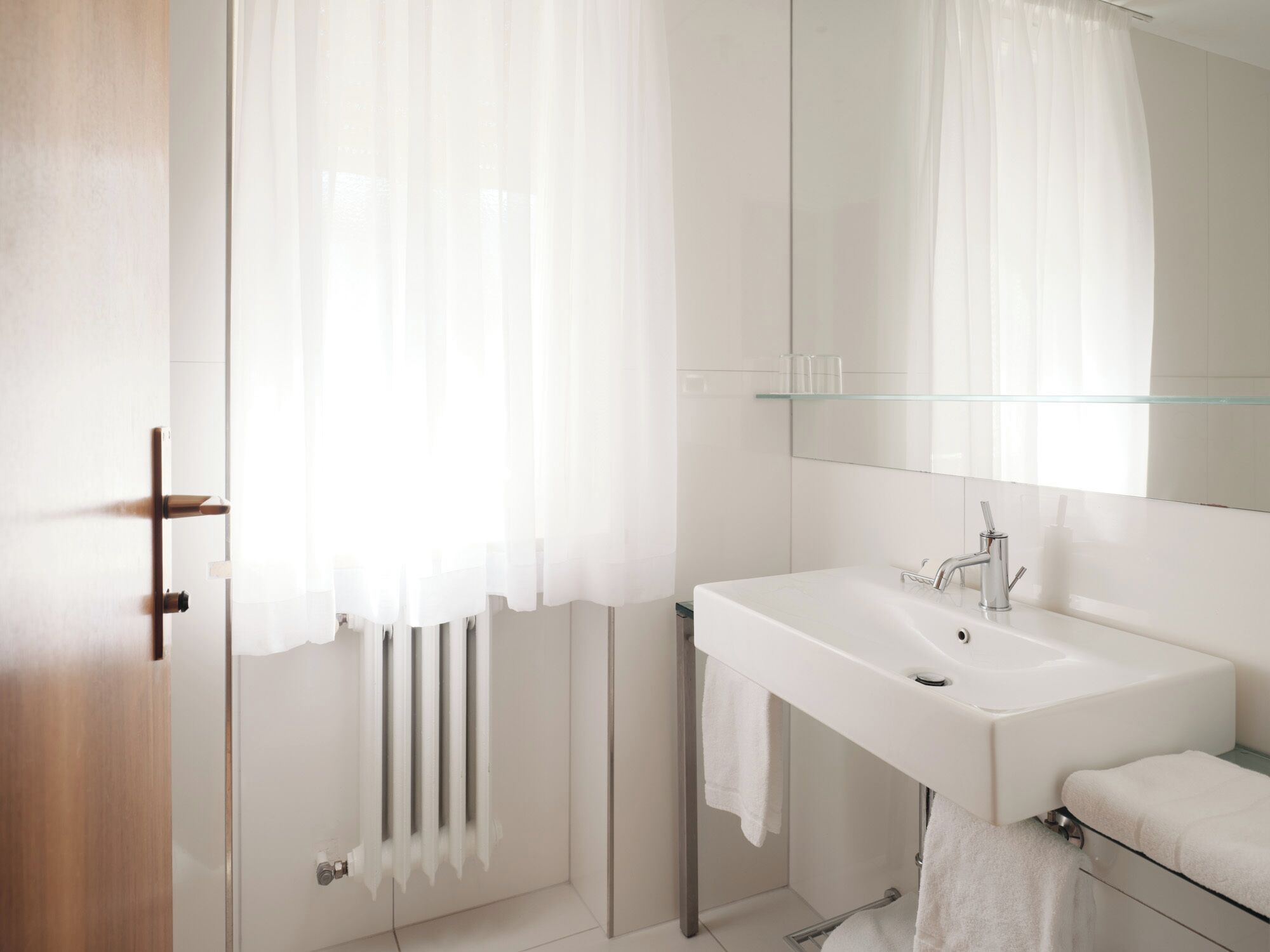 A modern bathroom with a white sink, mirror, and towel rack.