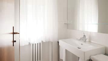 A modern bathroom with a white sink, mirror, and towel rack.