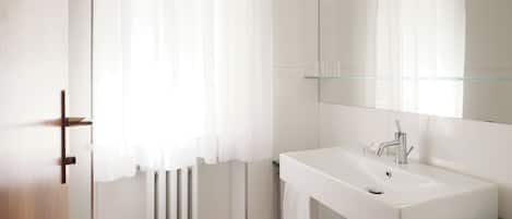 Un baño moderno con lavamanos, espejo y toallero blancos.