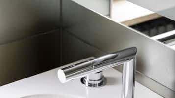 A modern bathroom with a white sink, chrome faucet, and a mirror reflecting the space.