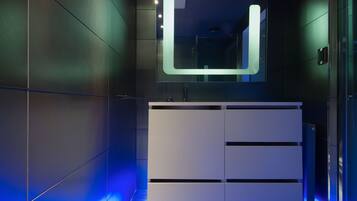 Un baño moderno con tocador blanco, un espejo grande e iluminación azul.