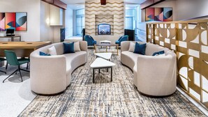 A modern hotel lobby with a curved seating area, a fireplace, and abstract wall art. - Holiday Inn Frisco by IHG (Frisco)
