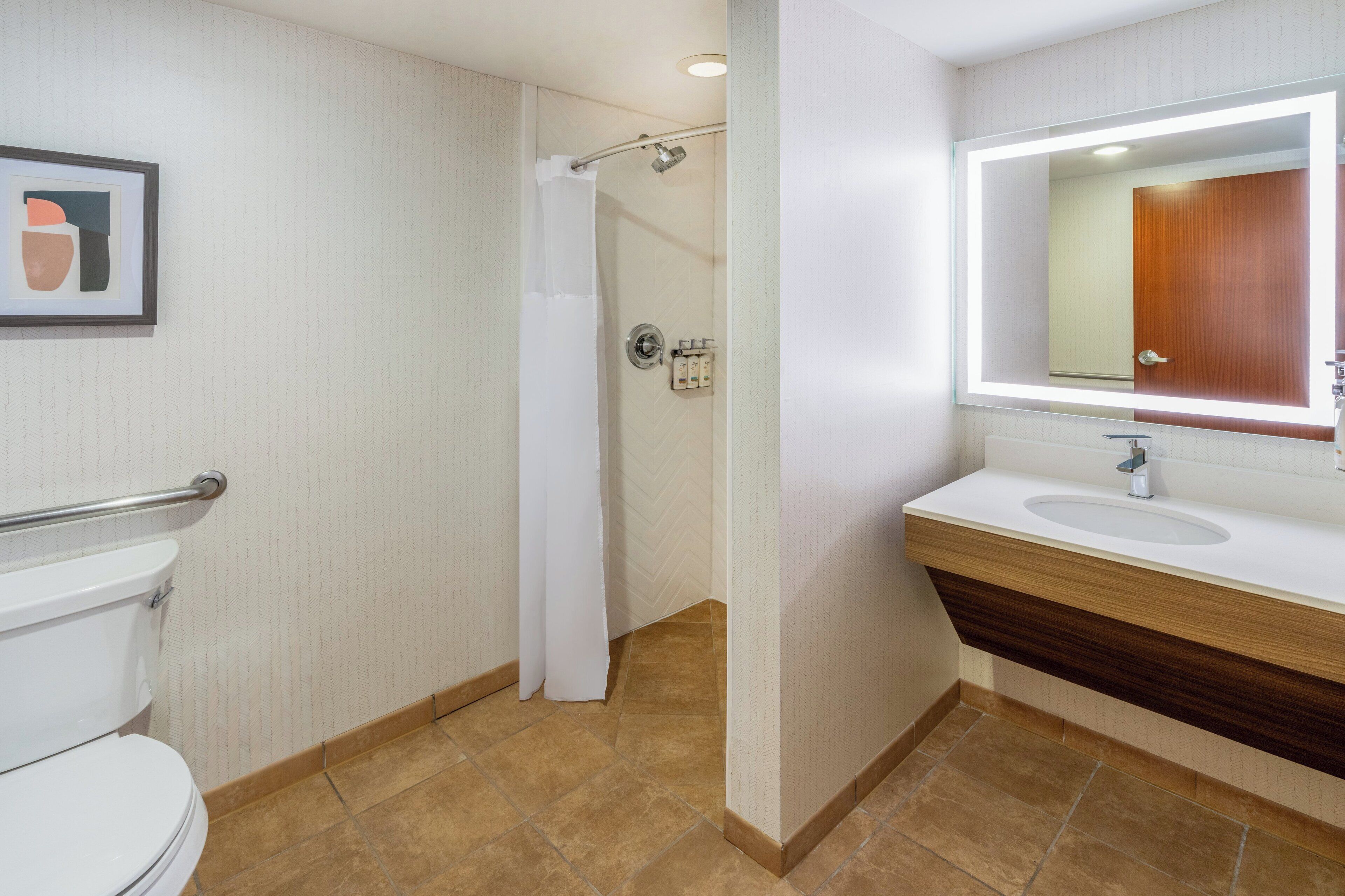 A modern bathroom with a toilet, shower, and sink.