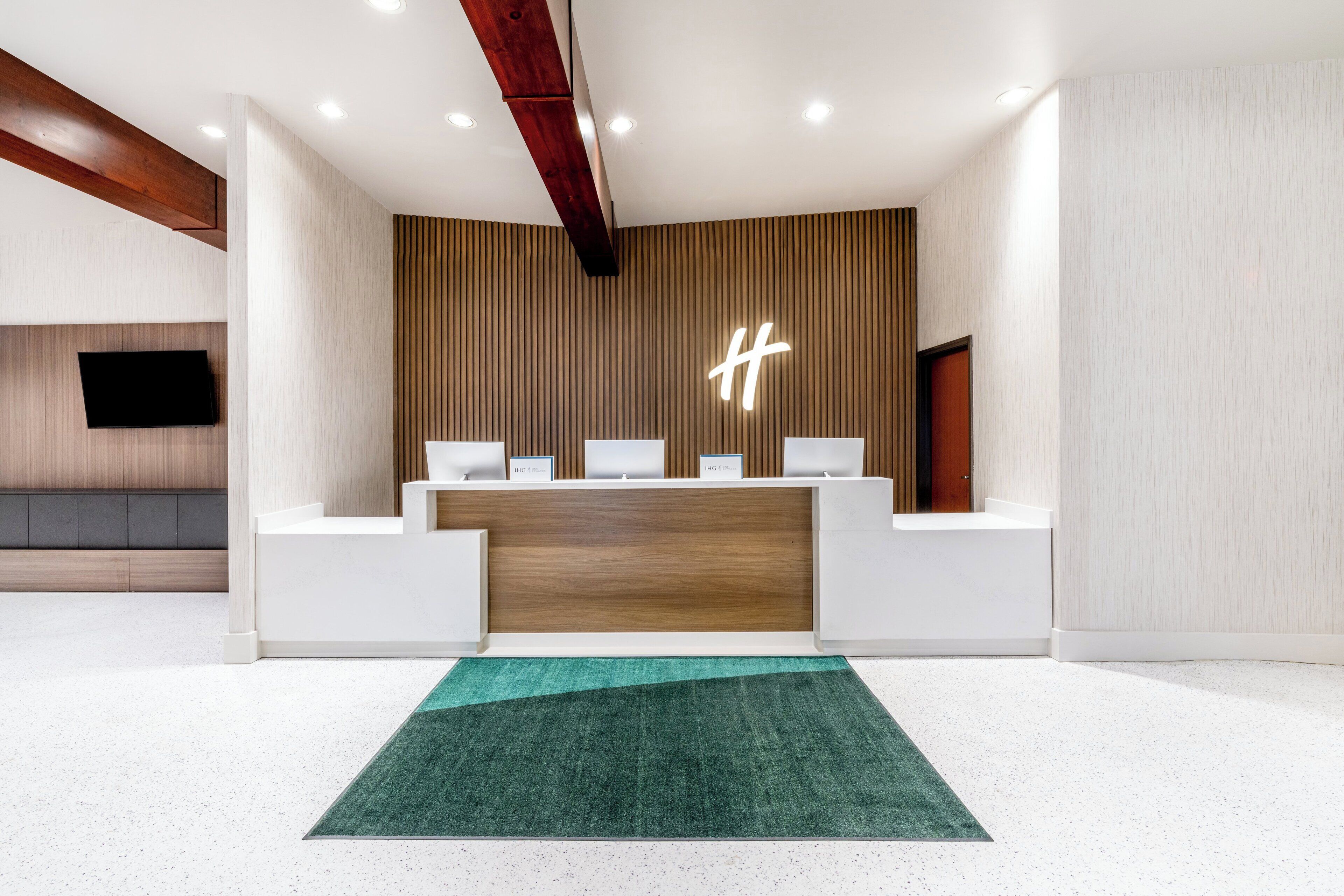 A reception area with a wooden reception desk, a green carpet, and a modern light fixture.