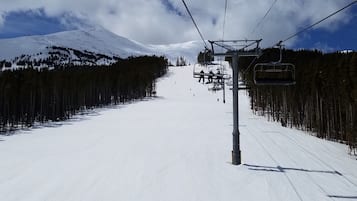 A ski lift chair moving along a snowy slope with a mountain in the background.