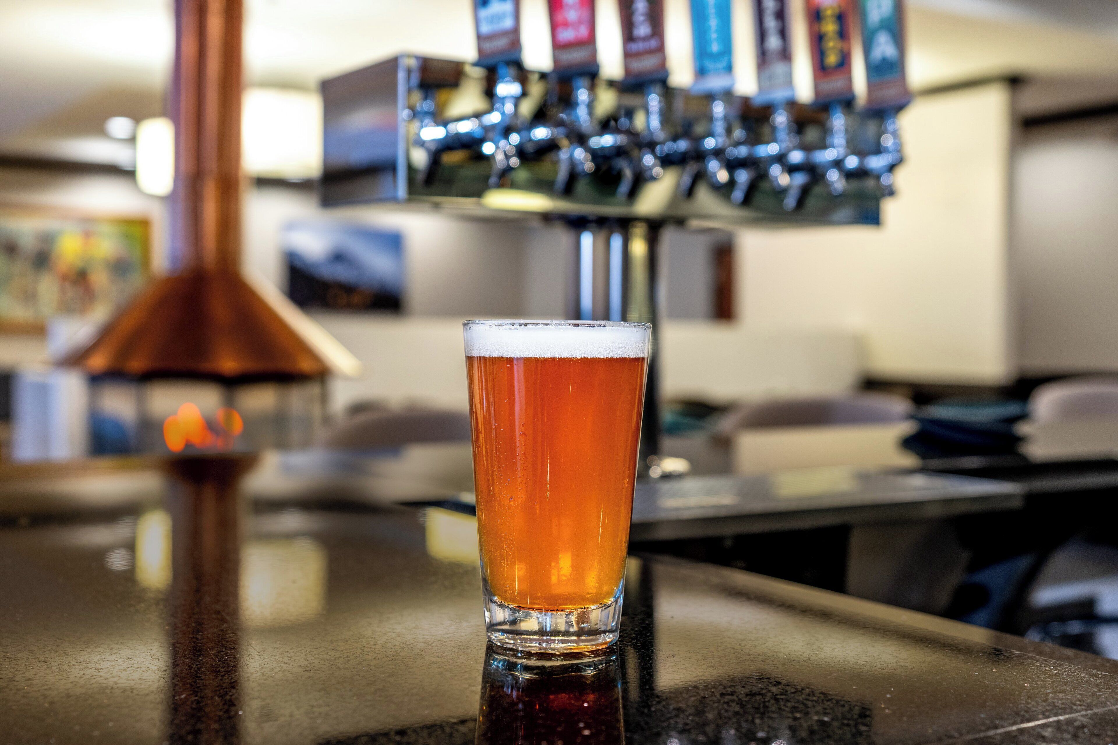 A glass of beer on a bar counter with a beer tap in the background.