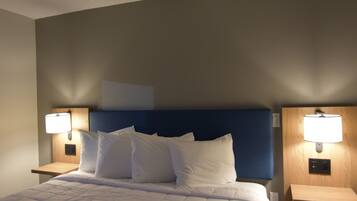 Habitación de hotel con una cama grande, dos mesitas de noche con lámparas, un cabecero azul y una alfombra estampada.